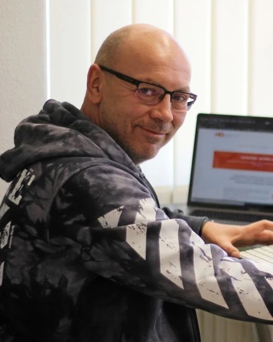 Mathias Goldhan, Geschäftsführer der HQ GmbH, lächelnd am Schreibtisch